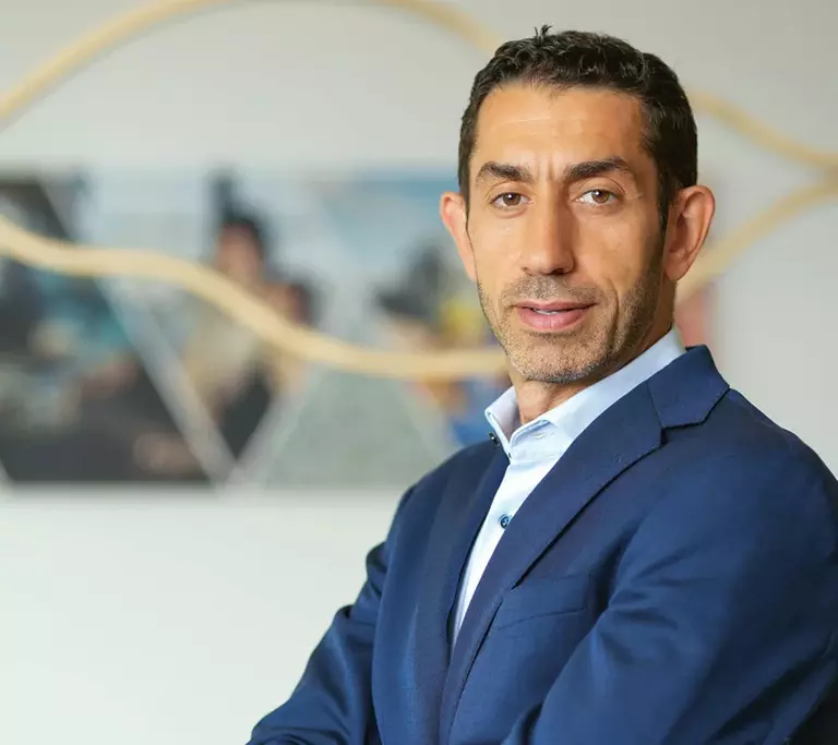 Porträt von Rakan Rahbani in blauem Anzug und hellblauem Hemd mit verschränkten Armen