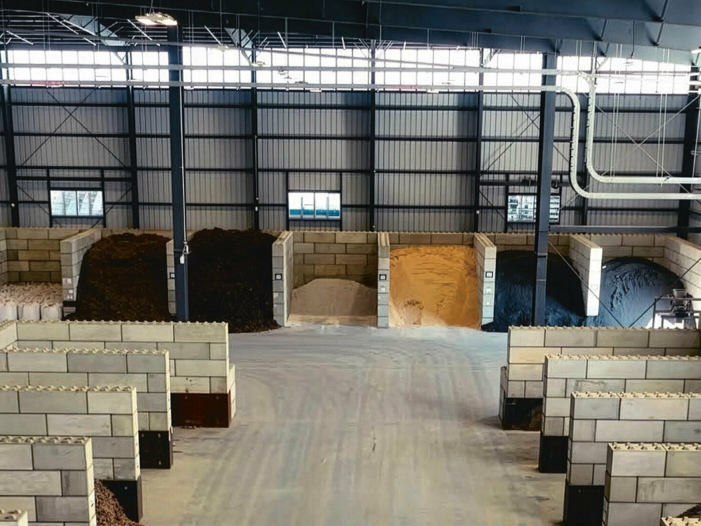 Innenansicht einer Lagerhalle mit durch Steinmauern getrennten Abteilen, in denen unterschiedliche Rohstoffe aufbewahrt werden