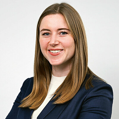 Porträt von Seonag Doherty, Vice President Corporate Development, mit blauem Blazer und weißem Shirt vor weißem Hintergrund