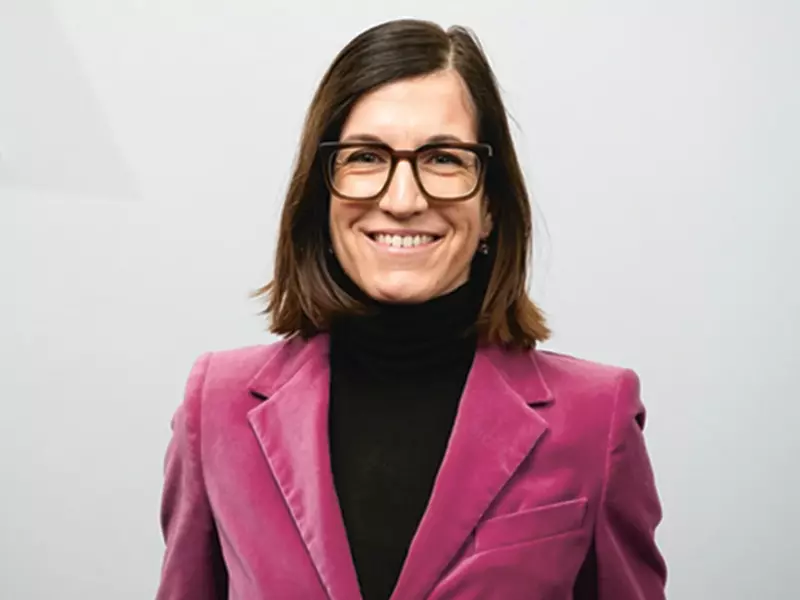 Laura Zielinski, Senior Vice President HR Group, mit Brille, schulterlangem braunen Haar, schwarzem Rollkragenpullover und pinkem Blazer.