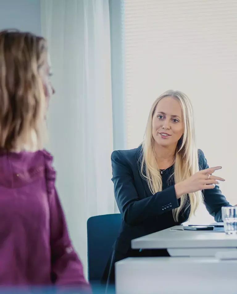 Gespräch von zwei Frauen und einem Mann an einem Tisch im Büro