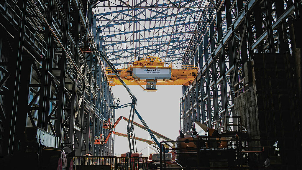 Fünfte Ebene der Aurubis Performance 2030: Focused Growth. Zu sehen ist eine riesige Lagerhalle, in deren Hintergrund sich mehrere Hebebühnen und Kisten auftürmen. 