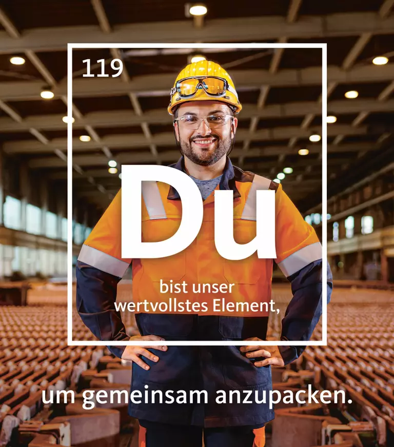 Lächelnder Werkarbeiter mit in die Hüften gestemmten Händen, der in einer Lagerhalle steht. Um ihn herum ein weißer Rahmen mit der Schrift: "Du bist unser wertvollstes Engagement, um gemeinsam anzupacken".