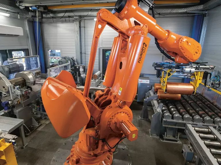 Orangener Roboterarm einer Stranggussanlage bei der Arbeit